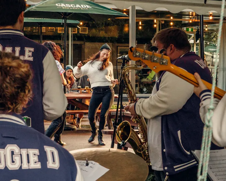 Person dancing in front of band of drums and saxophone players