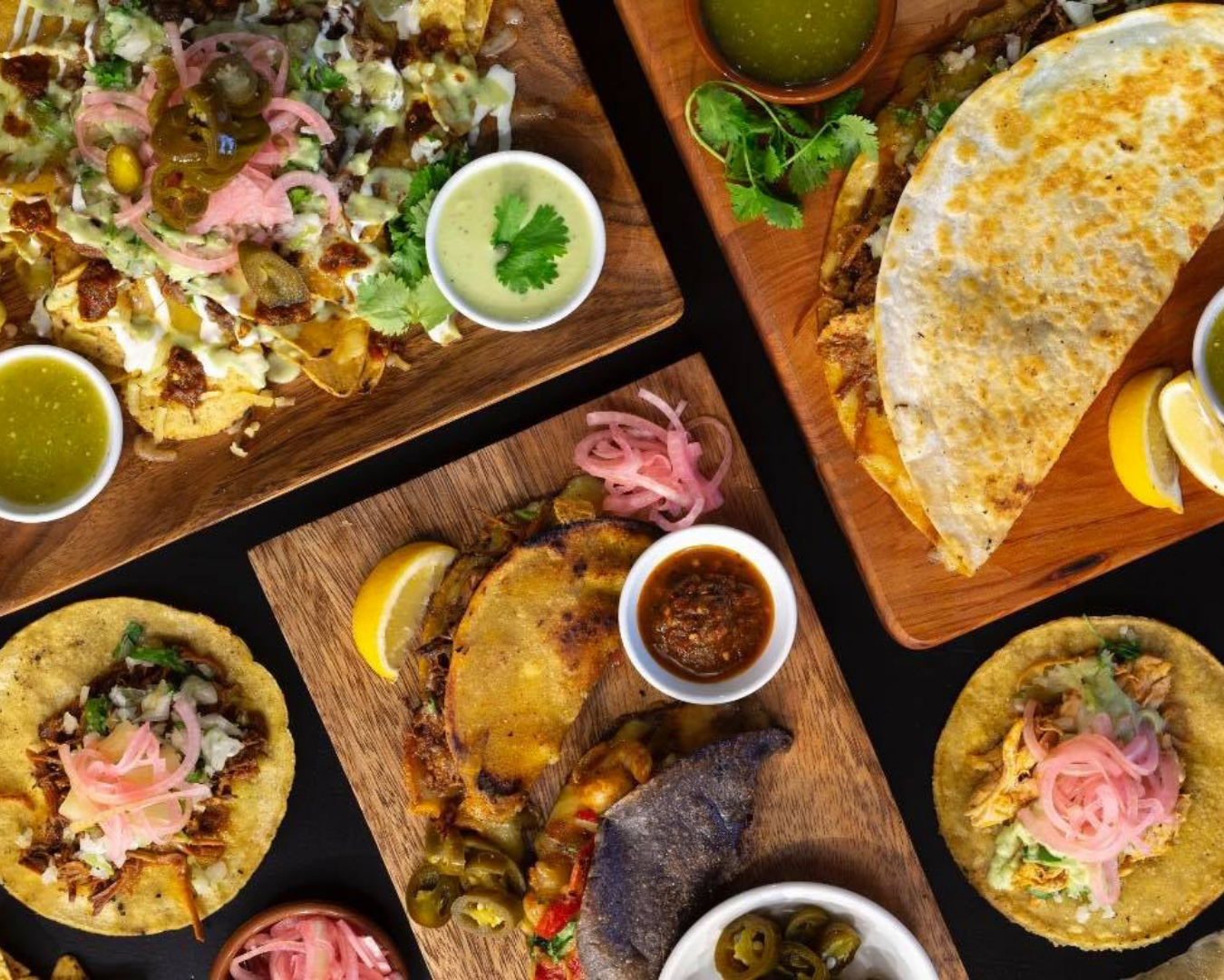 A range of dishes including Birria Tacos, Quesadillas and other tacos along with sauces and sides