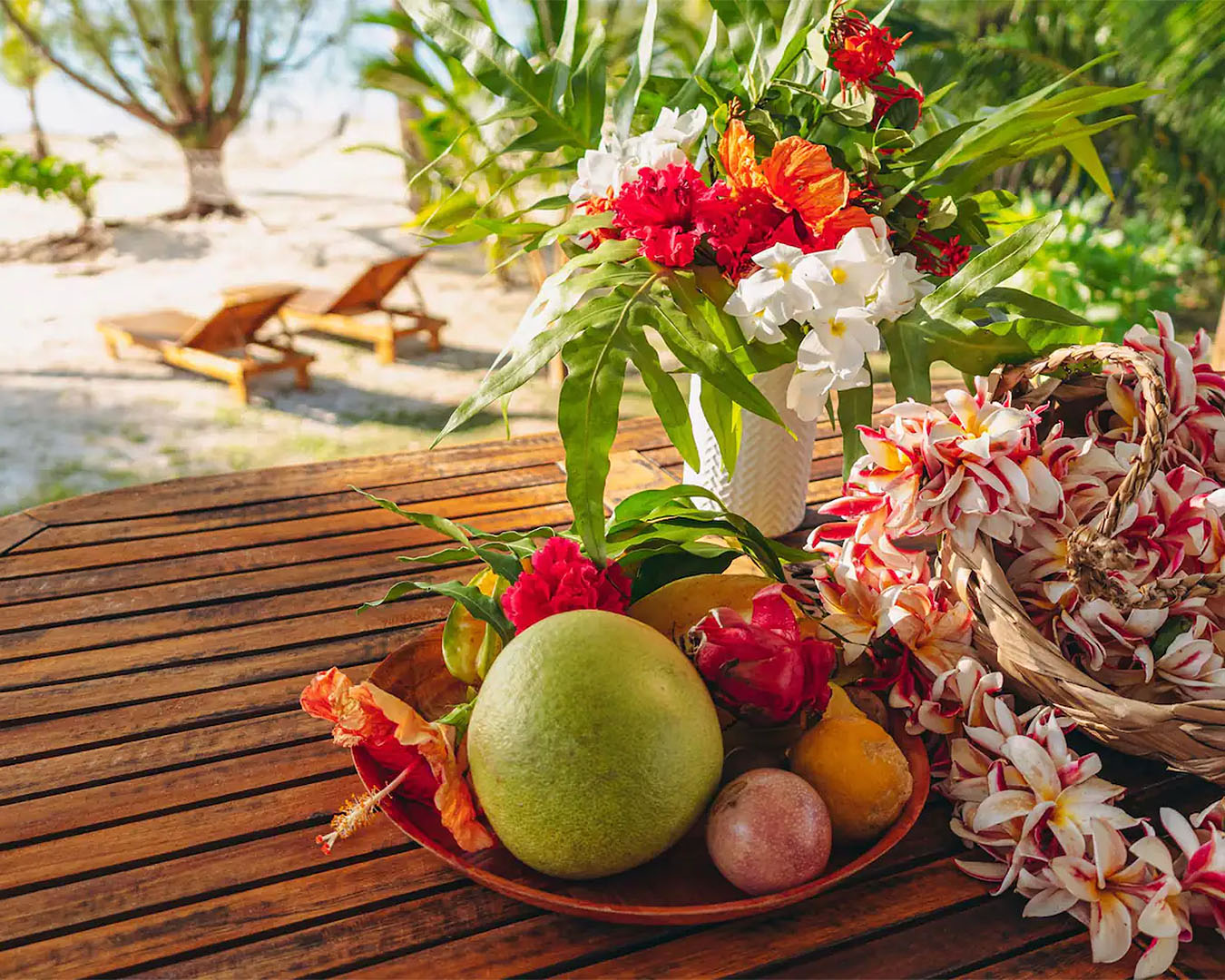 Fresh fruit on a table with sunloungers on the beach in the background.