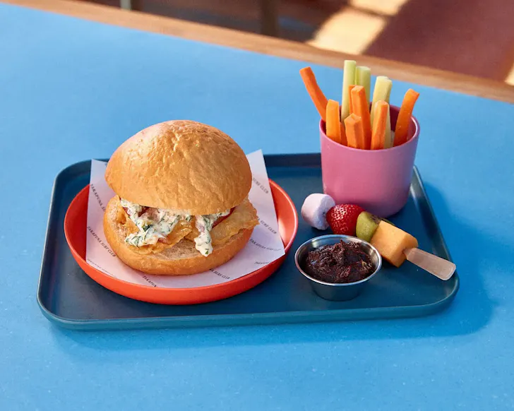 A cute kids menu with a burger, fruit stick and fries. 