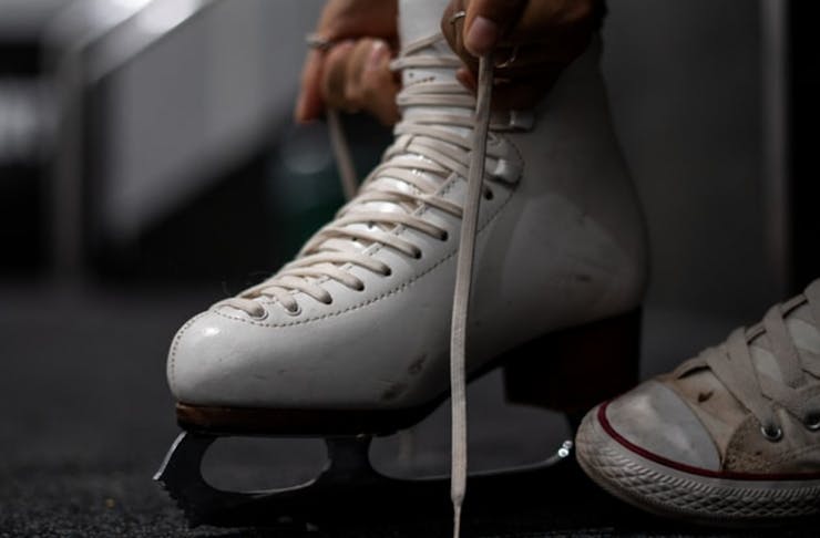 A close up image of a person putting ice skates on