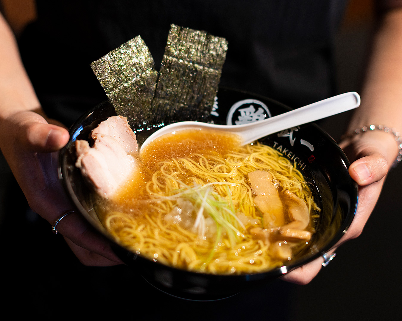 Someone holds a heaping bowl of ramen at Takeichi.