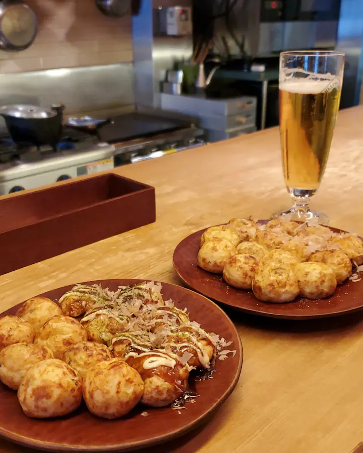 Two plates of yakitori with a pint of Japanese beer inside Takoriki, Osaka.