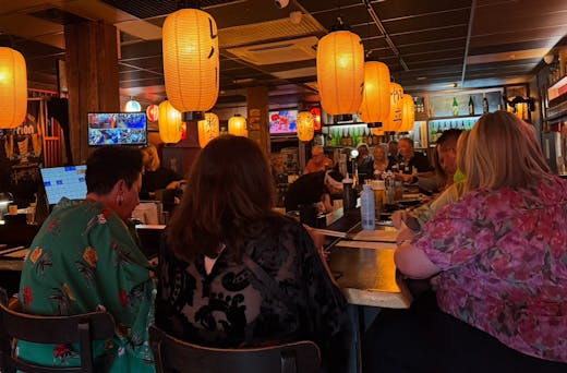 Several people sit around the high tables at Tanuki's wearing coloured kimonos. 