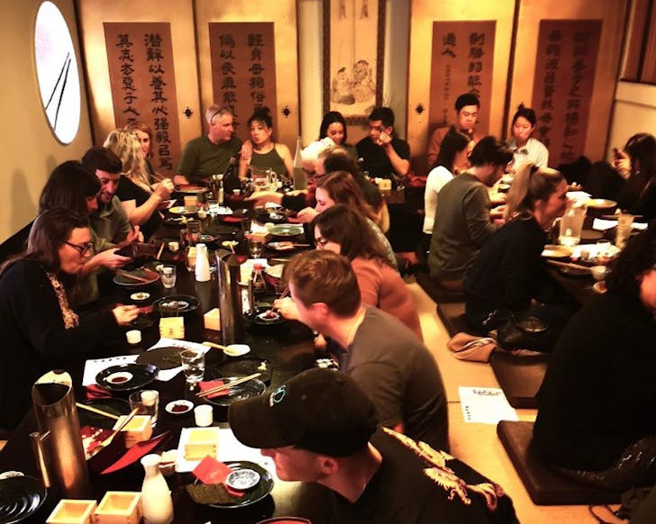 Rows of people sit on the floor around Japanese-style tables in Tanuki's private mezzanine. 