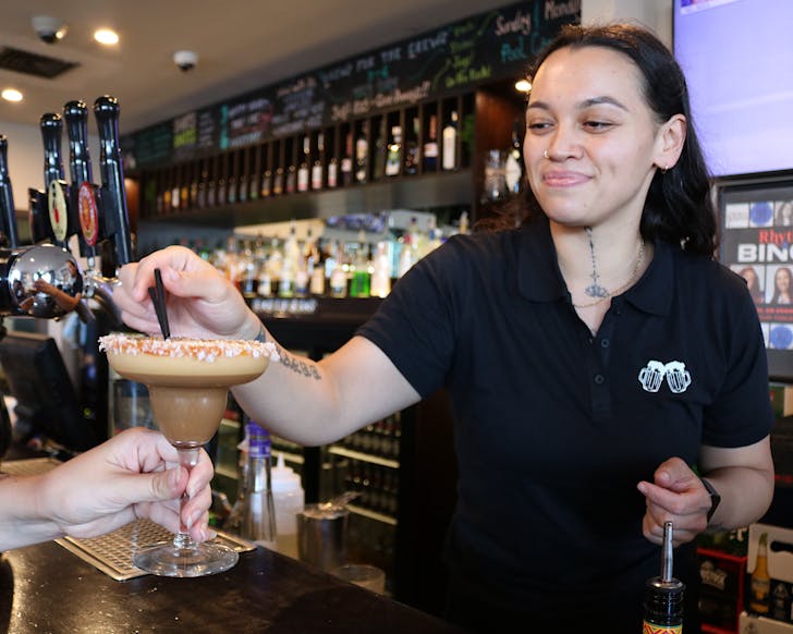 A bartender passes a salted caramel espresso martini to a customer at Taphouse. 