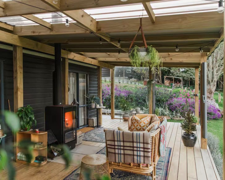 The fireplace on the outdoor deck with a couch at Tara Farm Cabin romantic Airbnb near Auckland