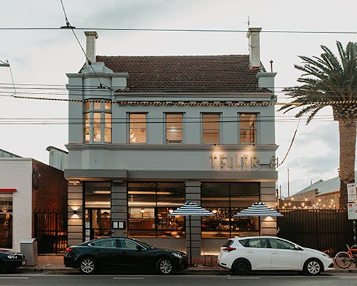 The exterior to Teller with cars out front and a palm tree.