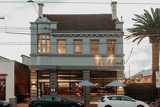 The exterior to Teller with cars out front and a palm tree.