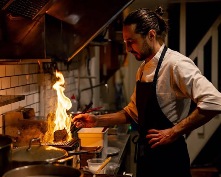 Chef Fabio cooks steak over an open flame in the kitchen at Tempero.
