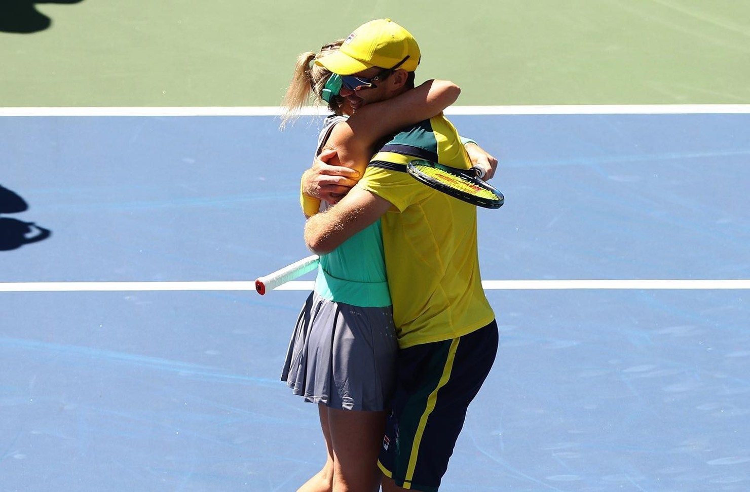 Two Australian tennis players hugging on court 