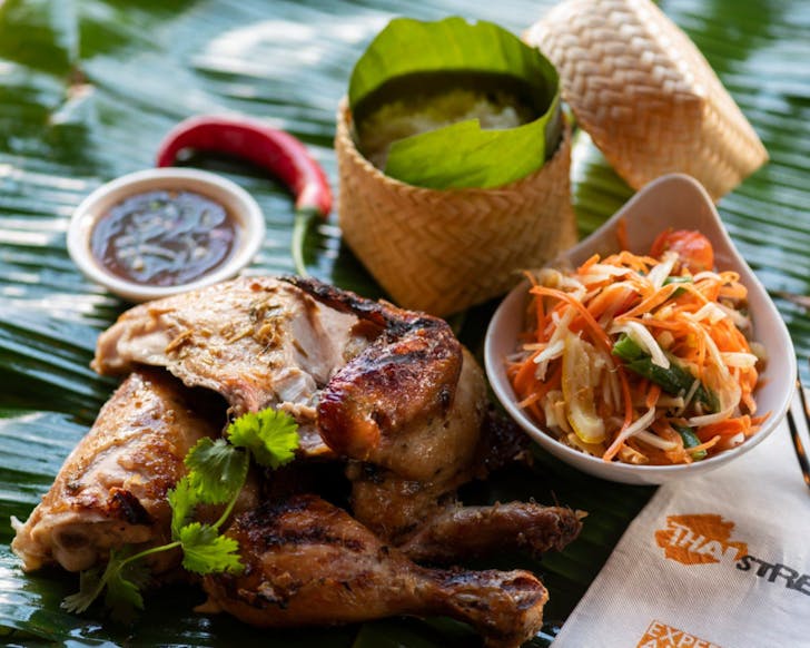 Chargrilled half chicken, sticky rice, som tum green papaya salad on a banana leaf