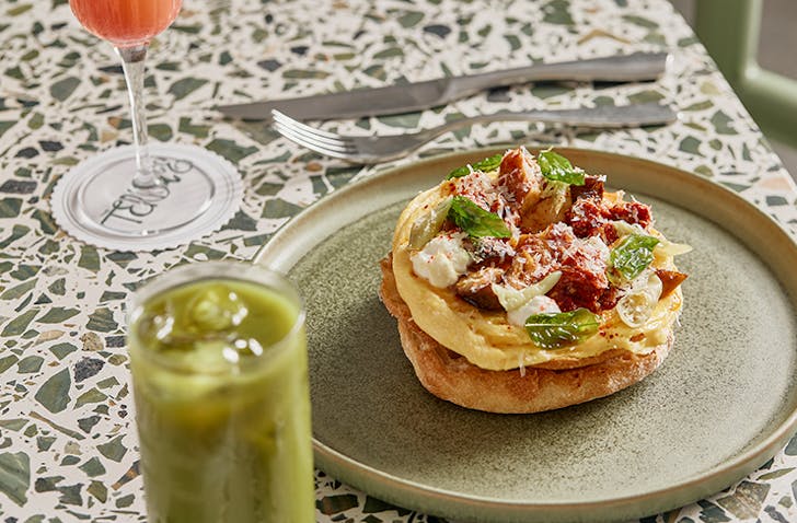 A green plate with a slice of toast topped with scrambled eggs and chorizo, one of Melbourne's best breakfast dishes