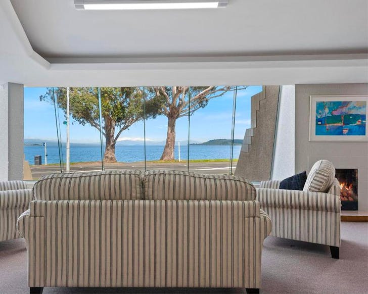 A pleasant room looks out over the lake while a fire roars in the corner.