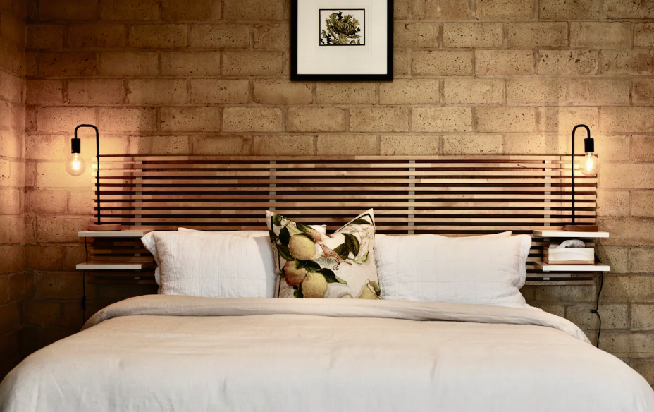 A bed white linen and a brick background, one of the best romantic getaways in Victoria.