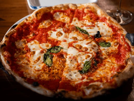 A perfectly cooked margherita pizza with cheese and basil on top.  