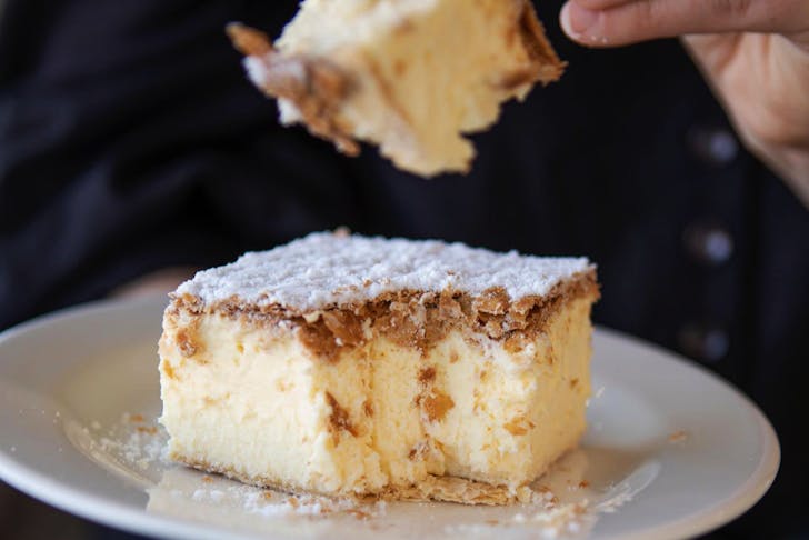 A person taking a forkful of a best vanilla slice melbourne. 