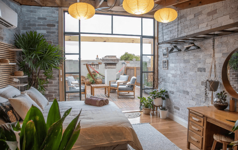 One of the prettiest and best airbnbs in Melbourne featuring plenty of lush green plants, brick walls, natural light and an inner city view via floor to ceiling windows.