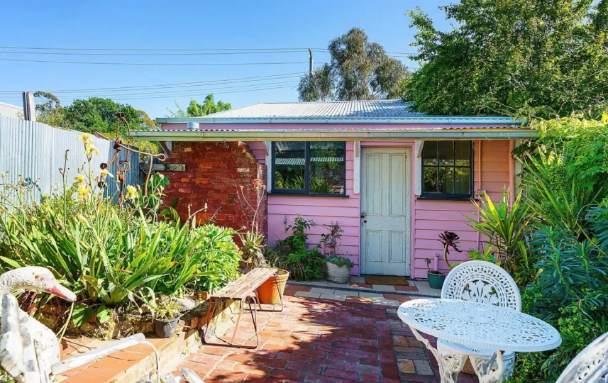 A backyard with a small pink cottage, a best romantic getaway in Victoria option.