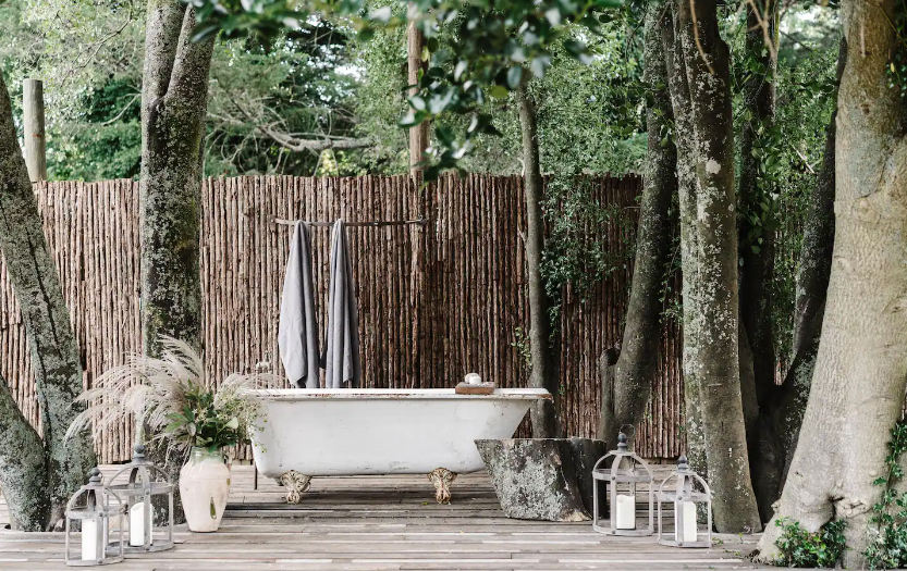 A large outdoor bathtub on a deck surrounded by trees at one of the best outdoor spa and bath airbnb in Victoria