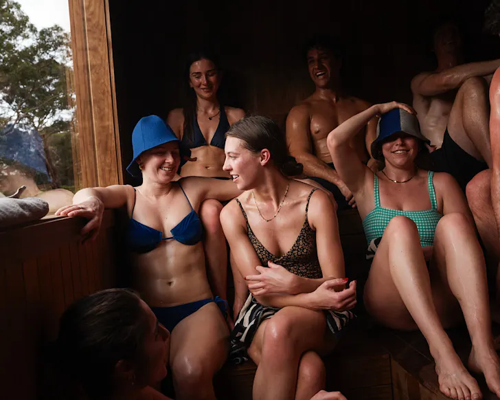 A group of people happily snug in a box sauna.