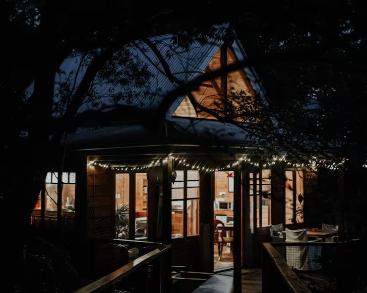 A view of The Bower Airbnb at night with its cosy lights on, it's one of the best romantic getaways in Australia