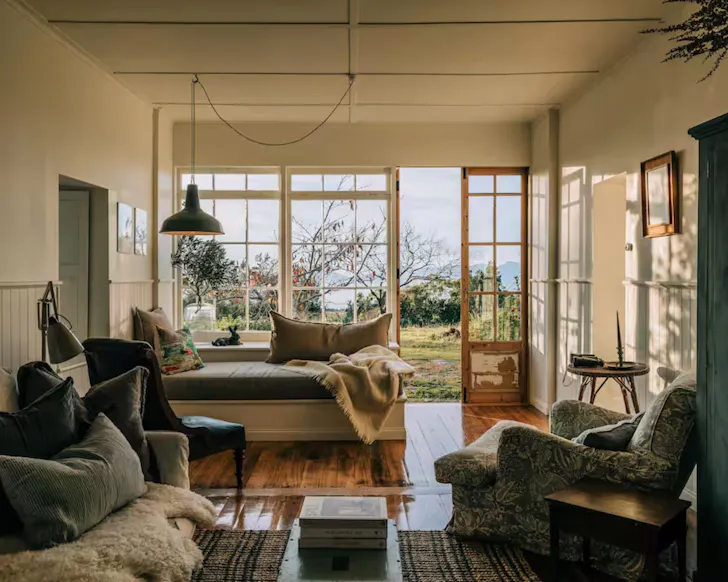 A view of the cosy living room with a window looking out to the water at The Burrows Tasmania
