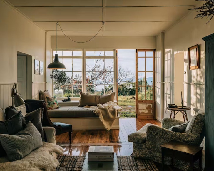 A view of the cosy living room with a window looking out to the water at The Burrows Tasmania