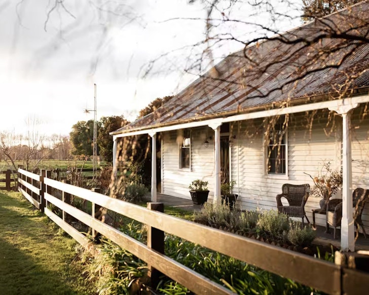 A view of the cute cottage surrounded by green fields at The Cottage at Dunmore Farm Airbnb one of the best romantic getaways in Australia