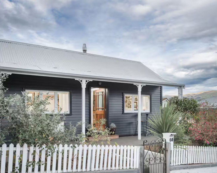 The exterior view of the blue weatherboard Airbnb The Daughter's Anchorage one of the best romantic stays in New Zealand