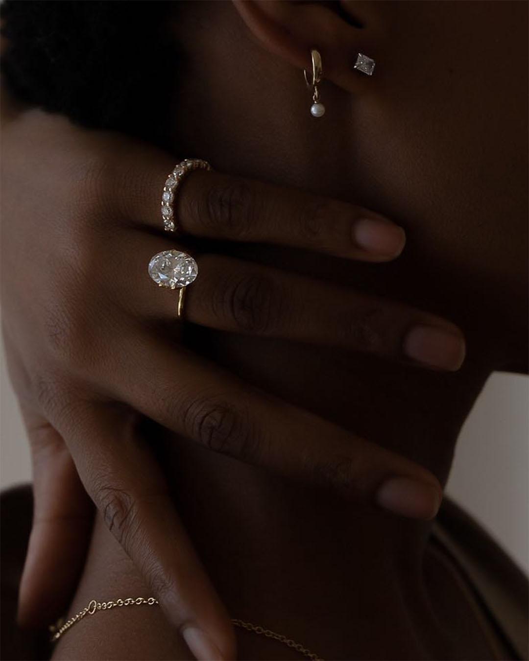 A woman with rings and earrings from The Diamod Shop.
