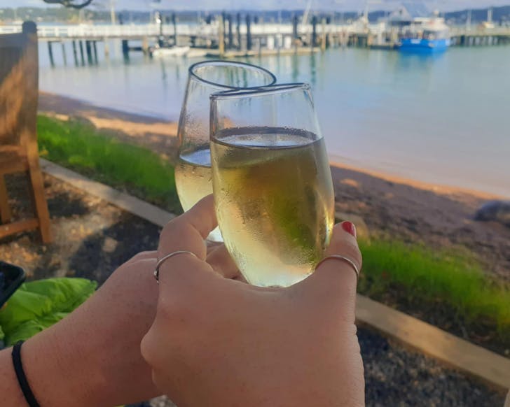 Clinking champagne glasses on the shore at Russell. 