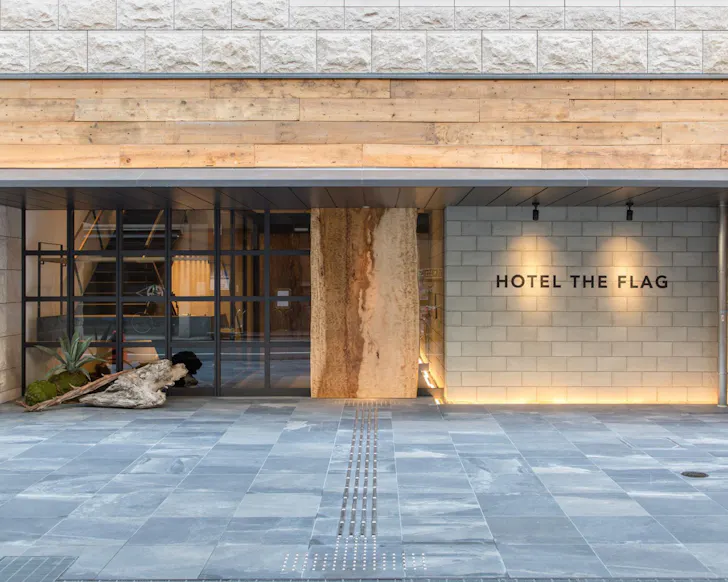 The minimalist stone and wood exterior of The Flag Hotel in Osaka. 