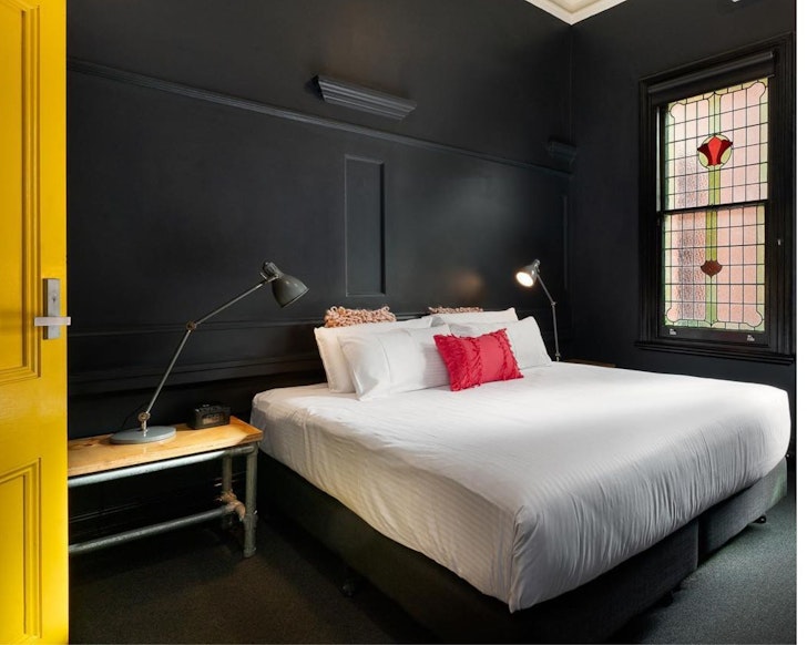 A yellow door opens into a quirky bedroom at The Franklin Hotel one of the best Adelaide hotels