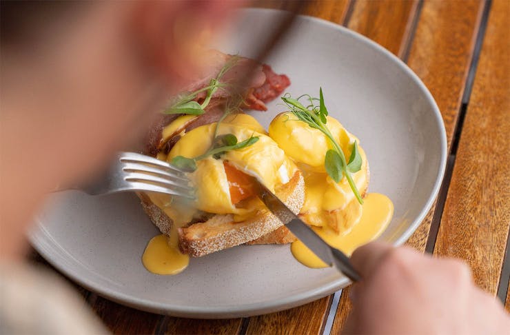 Someone tucks into a delicious eggs benny at The General.