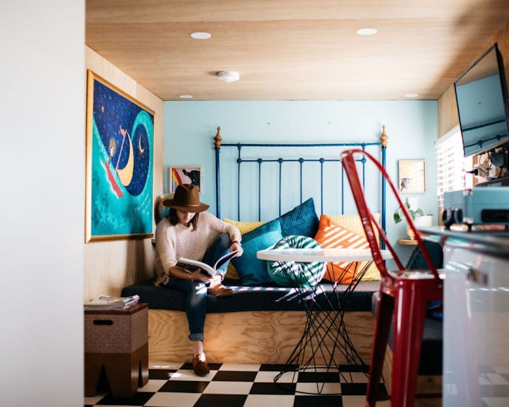 A woman sits on the bed at The Glampavan best tiny home stays WA