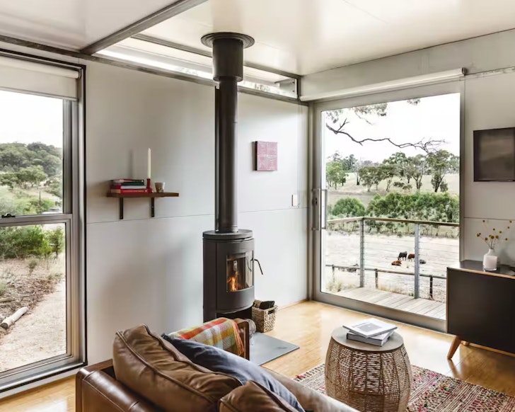 A view of the indoor fireplace and view through the window at The House on Soul Hill one of the best Adelaide Hills accommodation options