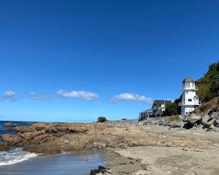 A view of The Lighthouse Airbnb next to the water, one of the most romantic stays in New Zealand