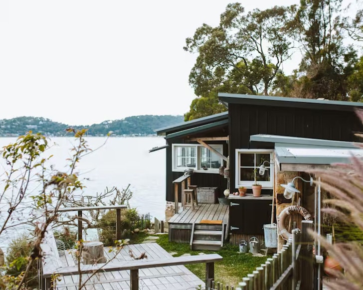 An exterior view of the The Little Black Shack on the water, some of the best Central Coast accommodation