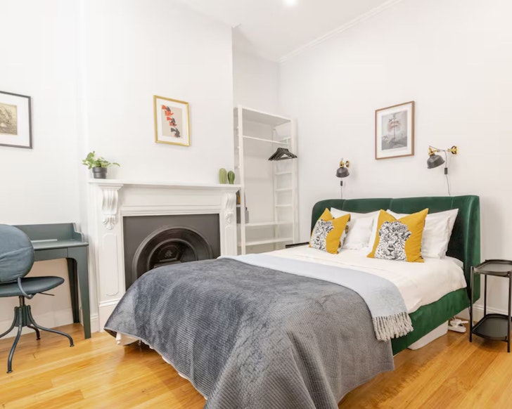 A view of the bedroom with fireplace and desk at The Little Sardine one of the best Airbnbs in Adelaide