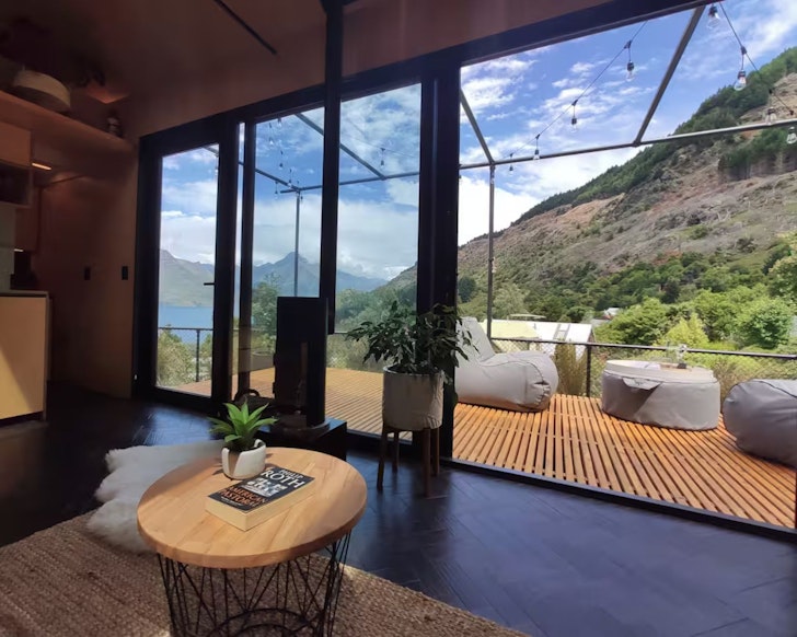 The living space looking out to the deck and the water at The Little Wanderer one of the best romantic stays in New Zealand