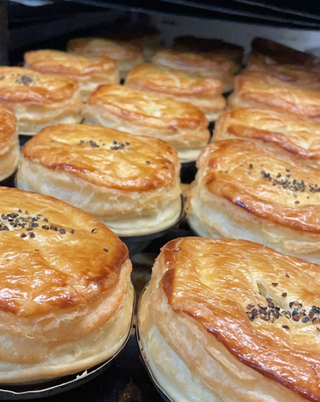 A tray of freshly baked and very puffed-up looking pies. 