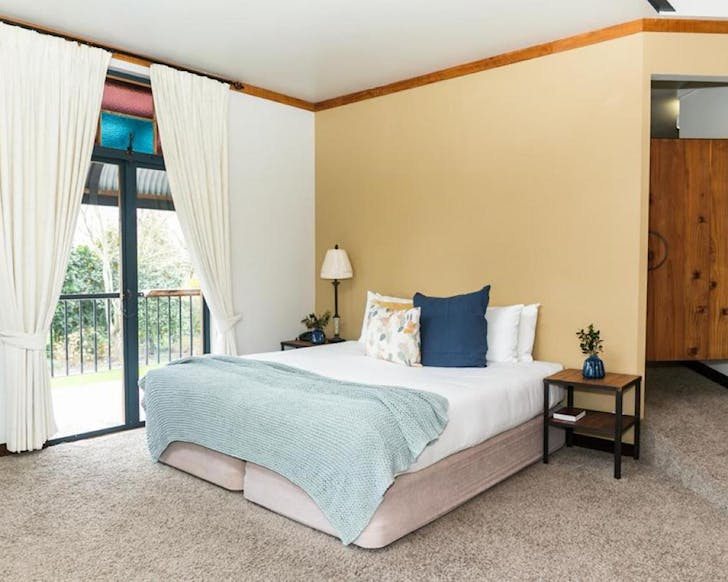 A cosy-looking bed and quirky blue and pink stained glass window features at The Narrows Landing Hotel, one of Hamiltonâs best hotels. 