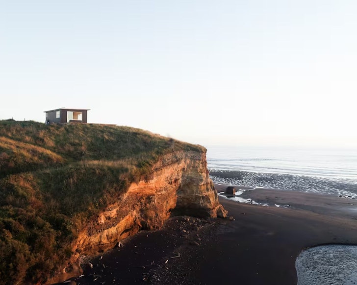A view of The Nest cosy cabin in New Zealand perched on the cliff top