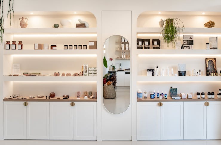White custom-made shelves are filled with wellness and clean beauty products at The Orangerie in Noosa, QLD.