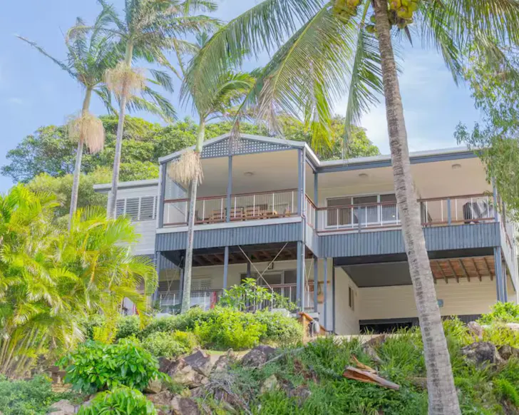 An exterior view of The Palm House surrounded by palm trees, one of the best beach houses near Brisbane