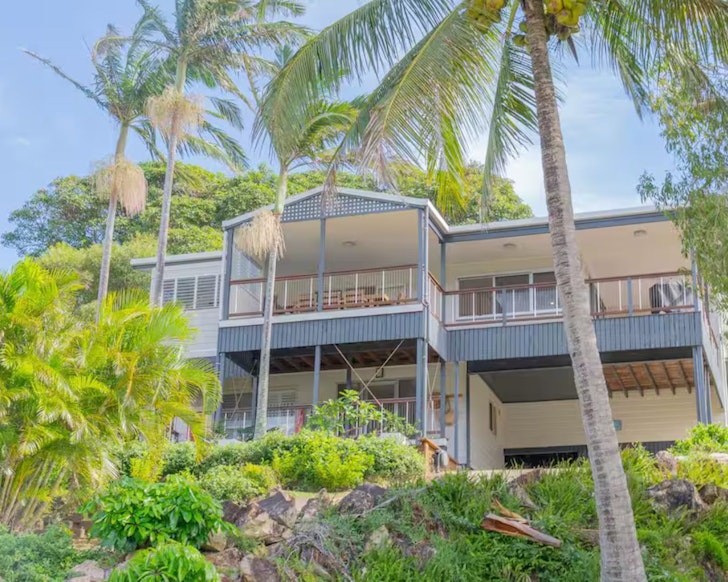 An exterior view of The Palm House surrounded by palm trees, one of the best beach houses near Brisbane