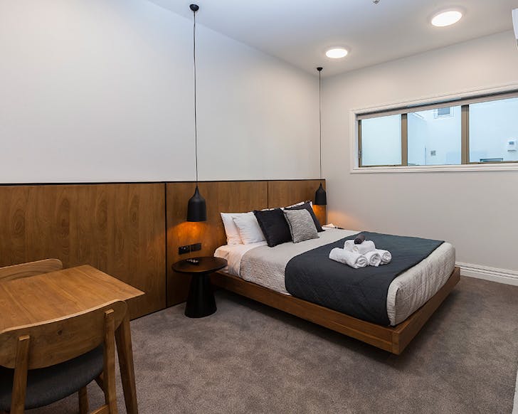 A chic, wood, white and dark blue accented boutique hotel room. 
