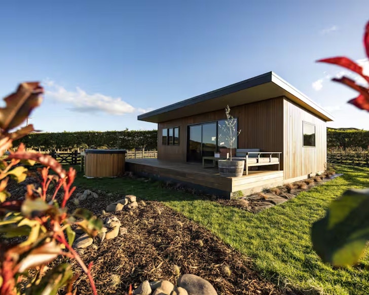 An exterior view of The Pheasants Nest cabin surrounded by farmland in New Zealand