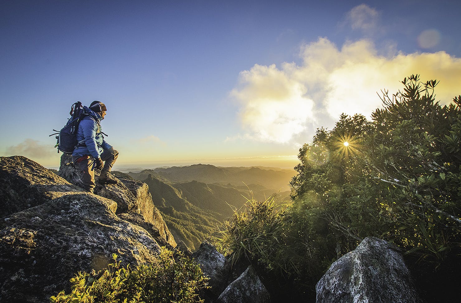 A man looks over the landscape at the top of The Pinnacles at sunset.